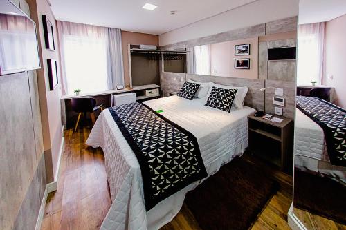 um quarto com uma cama com um cobertor preto e branco em Bristol Viçosa Hotel em Viçosa