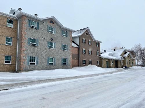 a snow covered street in front of a building at Residence & Conference Centre - Timmins in Timmins