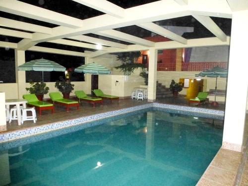 a swimming pool with green chairs and tables and umbrellas at HOTEL SAN ANDRES *** in Trujillo