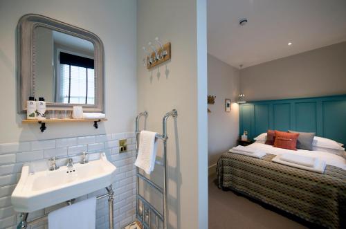 a bathroom with a sink and a bed with a mirror at The Coach House in Potton