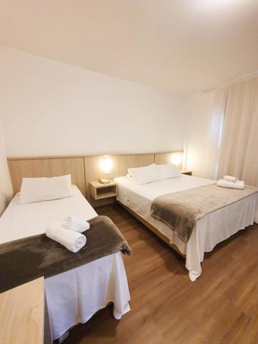 two beds in a room with two tables and towels at Avenida Palace Hotel in Joinville