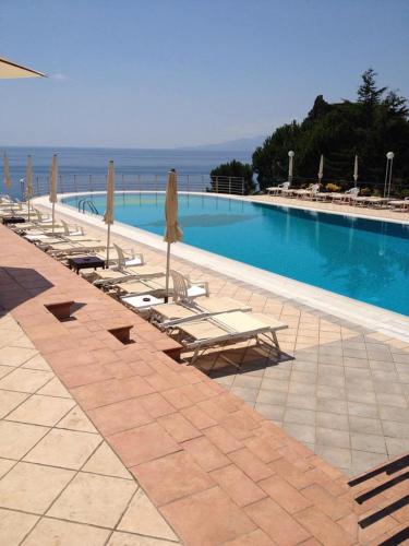 a pool with chairs and umbrellas next to the ocean at Hotel Club San Diego in Maratea