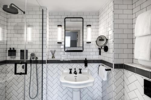 Baño blanco con lavabo y espejo en Victory House Leicester Square, en Londres