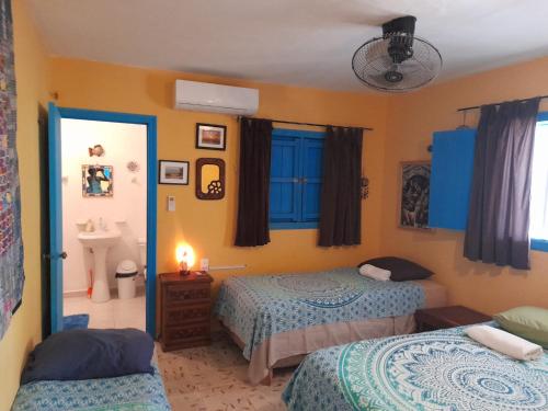 - une chambre avec 2 lits, un lavabo et un miroir dans l'établissement La Casa del Ritmo, à El Cuyo