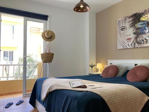 una camera da letto con un letto e un dipinto sul muro di Precioso apto 4 pers, 2 piscinas, fibra óptica a Corralejo