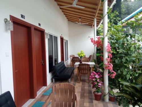 a porch with a table and chairs and flowers at Thoddoo Garden inn in Thoddoo