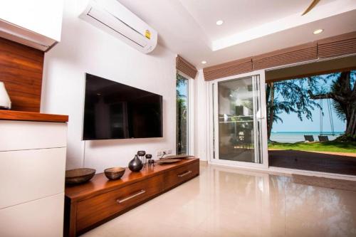 a living room with a tv and a large window at Siam Sunset Beach Villas in Ko Chang