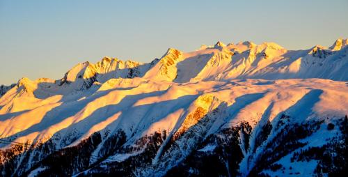 a snow covered mountain with the sun shining on it at Hotel Fiescherhof in Fiesch