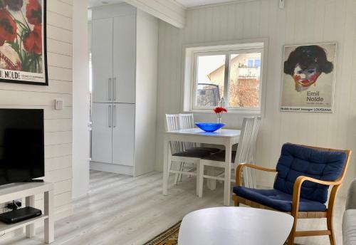 a living room with a table and a tv at Helgas Hus tre rum o kök in Hunnebostrand