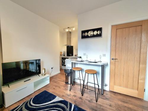 een woonkamer met een tafel en 2 krukken bij Modern Apt near Train Station and Ideal for Long Stays in Leicester