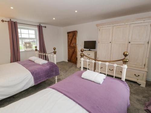 twee bedden in een slaapkamer met paars en wit bij Bodrual Cottage in Caernarfon