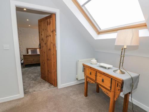 a room with a table with a lamp and a mirror at Bodrual Cottage in Caernarfon