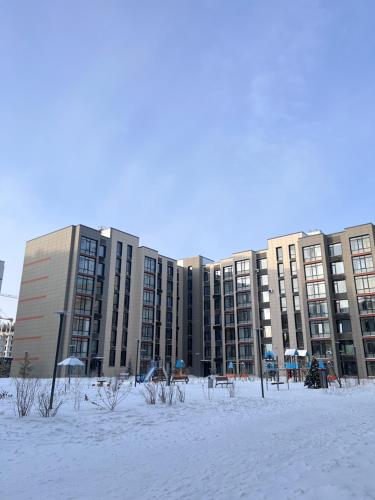 a large building in the snow with benches in front of it at Квартира in Astana