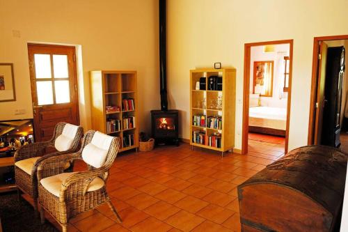 ein Wohnzimmer mit einem Sofa, Stühlen und einem Kamin in der Unterkunft Vale do Guizo: Casa Poente on the contryside, close by the sea. in Aljezur