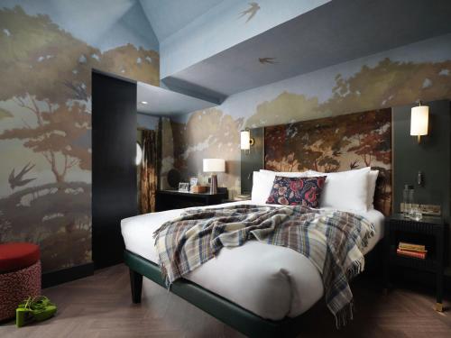 a bedroom with a large bed with a painting on the wall at The Other House South Kensington in London