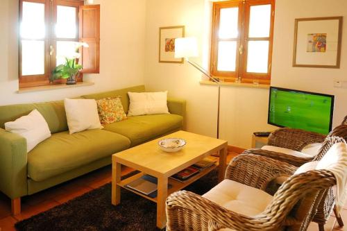 uma sala de estar com um sofá verde e uma televisão em Vale do Guizo: Casa Poente on the contryside, close by the sea. em Aljezur