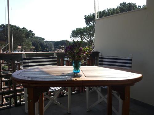 una mesa de madera con un jarrón de flores en el balcón en Il Cinqualino locazione turistica, en Cinquale