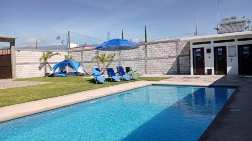 特來亞卡潘的住宿－Maktub TlayaGlamping，一个带2把蓝色椅子和遮阳伞的游泳池