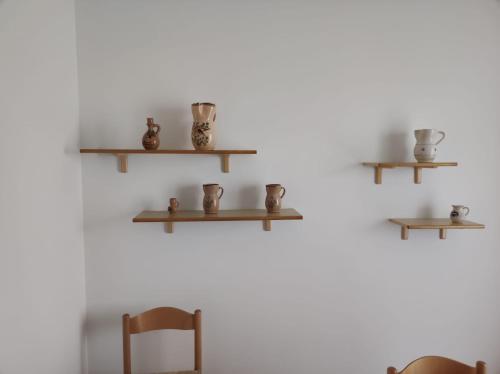 eine Wand mit Holzregalen mit Tassen und einem Stuhl in der Unterkunft Casa Vacanze Riccio di Mare in Santa Maria di Leuca
