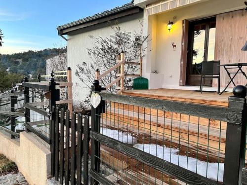 ein Haus mit einer Holzveranda mit einem Zaun in der Unterkunft Location studio jardin/terrasse in Gréolières