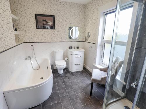 a bathroom with a tub and a toilet and a window at Coastguard Cottages in Hull