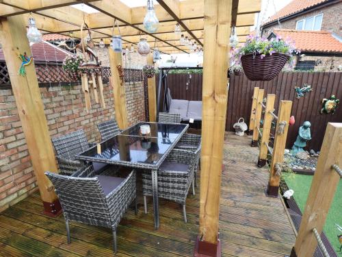 a patio with a table and chairs on a wooden deck at Coastguard Cottages in Hull