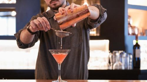 a man is making a drink in a martini glass at Mercure Saint-Lary in Saint-Lary-Soulan