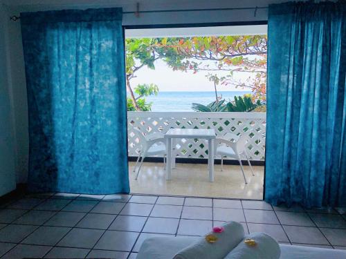 a room with a view of the ocean from a balcony at Sand and Tan Beach Hotel in Ocho Rios