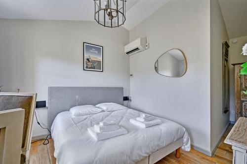 Schlafzimmer mit einem Bett mit weißer Bettwäsche und einem Spiegel in der Unterkunft Au cœur des Papes, dans bâtisse de charme studios & appartements en cœur de ville in Avignon
