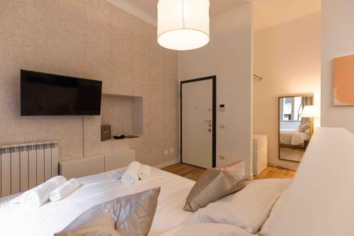 a bedroom with a white bed and a flat screen tv at Divini Gae Aulenti in Milan