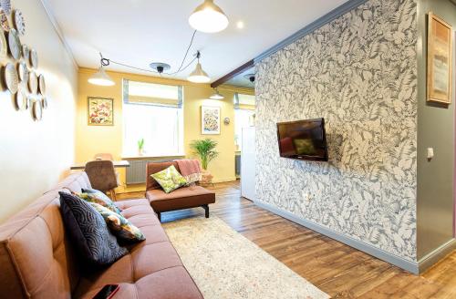 een woonkamer met een bank en een tv aan de muur bij Self check in Miera Art Apartment in Rīga