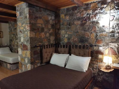 a bed in a room with a stone wall at Ataviros Hotel in Émbonas