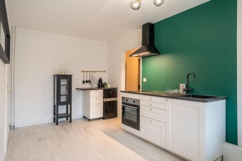 une cuisine avec des armoires blanches et des murs verts dans l'établissement Appartement Cosy Art Déco/ Proche centre-ville, à Nantes