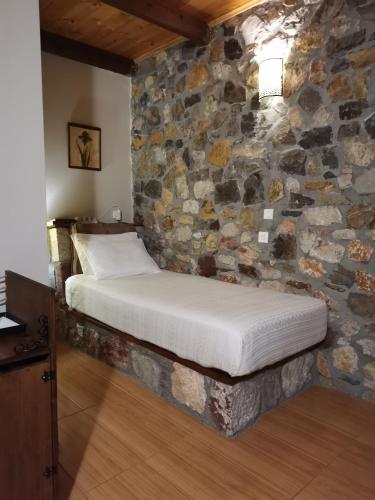 a bed in a room with a stone wall at Ataviros Hotel in Émbonas