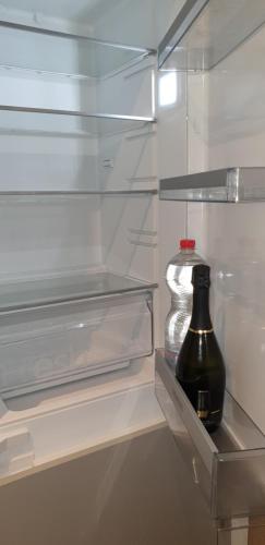 una nevera vacía con una botella en un estante en modern appartament en Porlezza