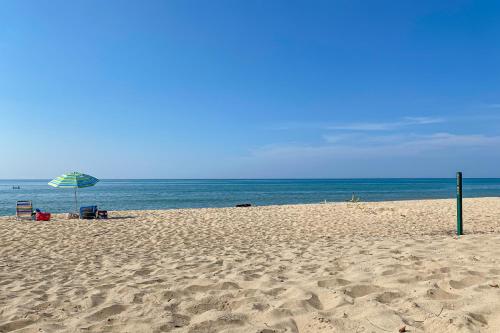 a beach with an umbrella and chairs and the ocean at The Gatehouse on Orchard Beach in Lakeside