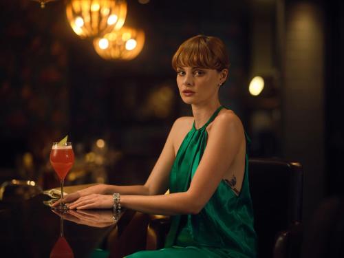 a woman in a green dress holding a drink at The Other House South Kensington in London