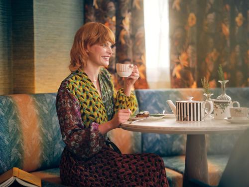 a woman sitting at a table drinking a cup of coffee at The Other House South Kensington in London