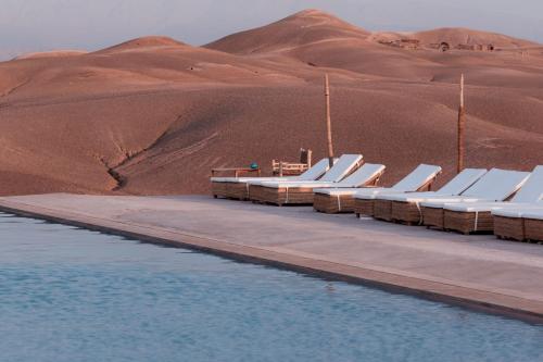 a row of white chairs on a dock in the desert at Alkamar Camp Agafay in El Karia