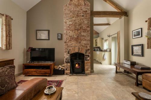 a living room with a brick fireplace with a tv at Irishman's Cottage in York