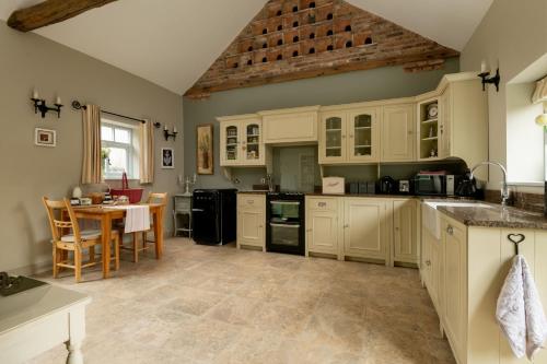 uma cozinha com armários brancos e uma mesa em Irishman's Cottage em York