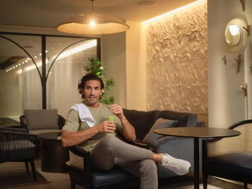 a man sitting in a chair holding a drink at The Other House South Kensington in London