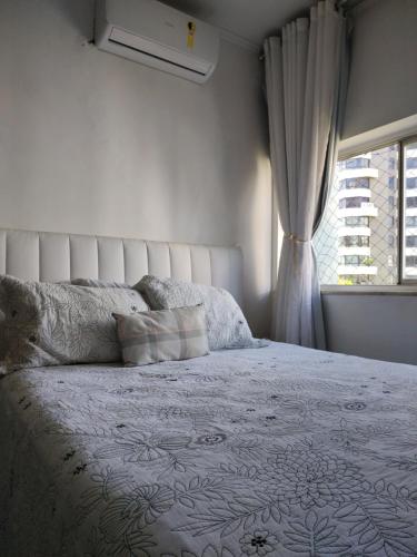 1 dormitorio con 1 cama blanca y ventana en Carnaval Salvador, en Salvador