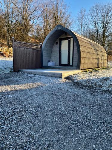 a small building with a curved roof on a gravel road at Glamping Pods in Milngavie