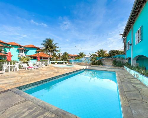 a swimming pool in front of a house with a blue building at Pousada Paraíso do Atlântico in Arraial do Cabo