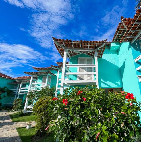 a blue building with red flowers in front of it at Pousada Paraíso do Atlântico in Arraial do Cabo