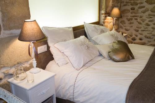 a bed with white sheets and pillows and two lamps at Le Val des Sens in Chatte