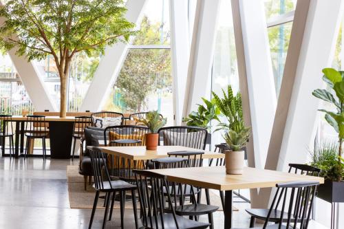 a restaurant with tables and chairs and plants at Best Western M-Treize Paris Asnieres in Asnières-sur-Seine