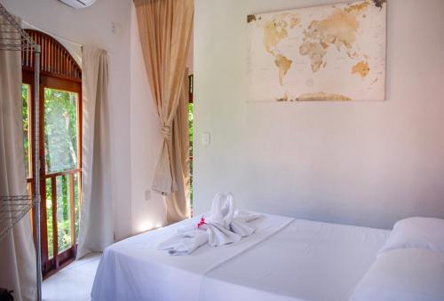 Una cama blanca en una habitación con un mapa en la pared en Apartamentos GoPipa934, en Pipa