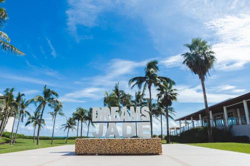 a sign in front of a building with palm trees at Dreams Jade Resort & Spa - All Inclusive in Puerto Morelos